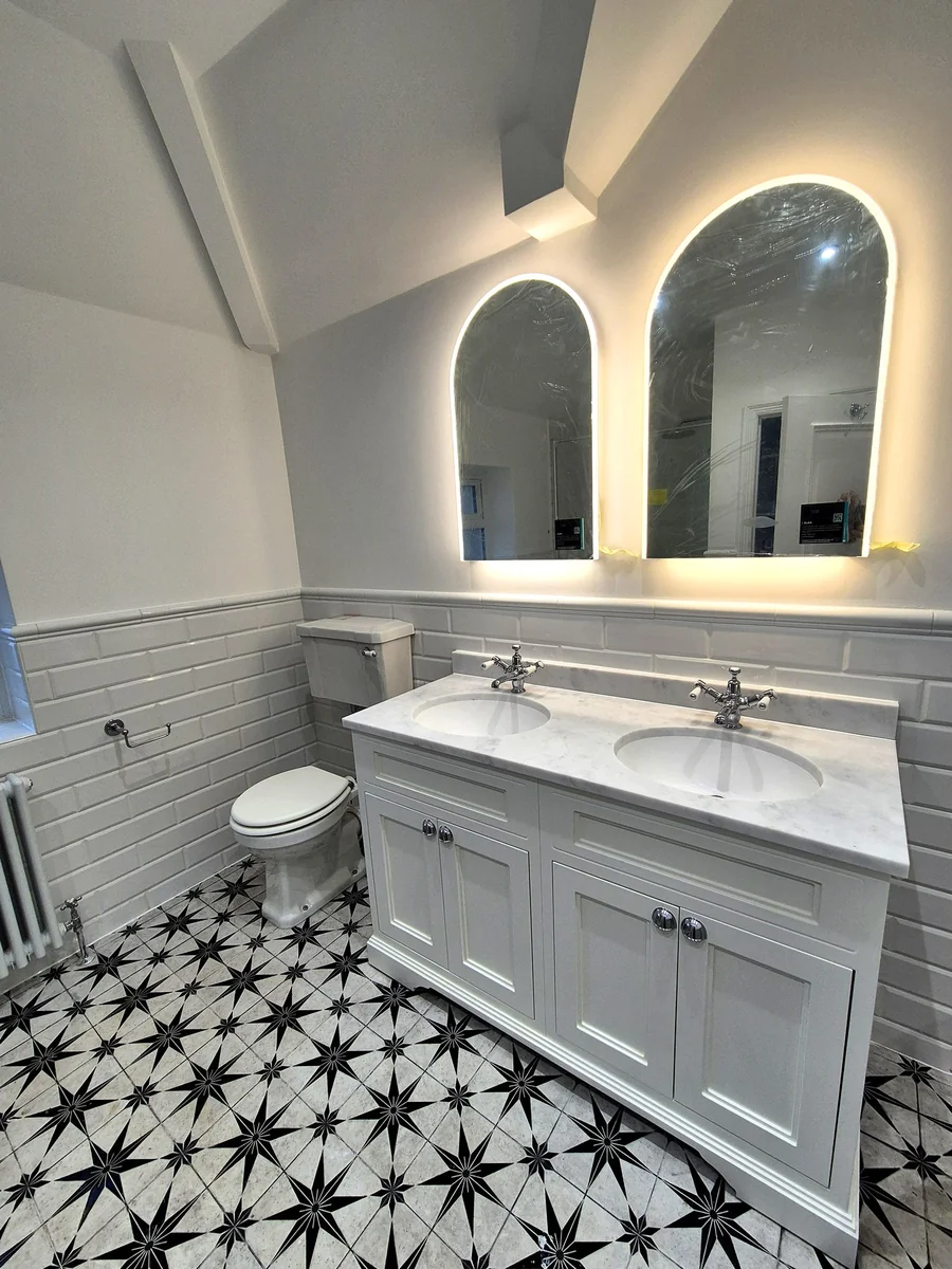 Classic white bathroom with star-pattern floor and arched LED mirrors